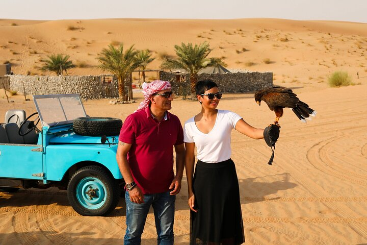 Experience the allure of the desert with a vintage Land Rover ride meet friendly falcons and savor traditional Emirati breakfast amidst stunning dunes and rich Bedouin heritage.